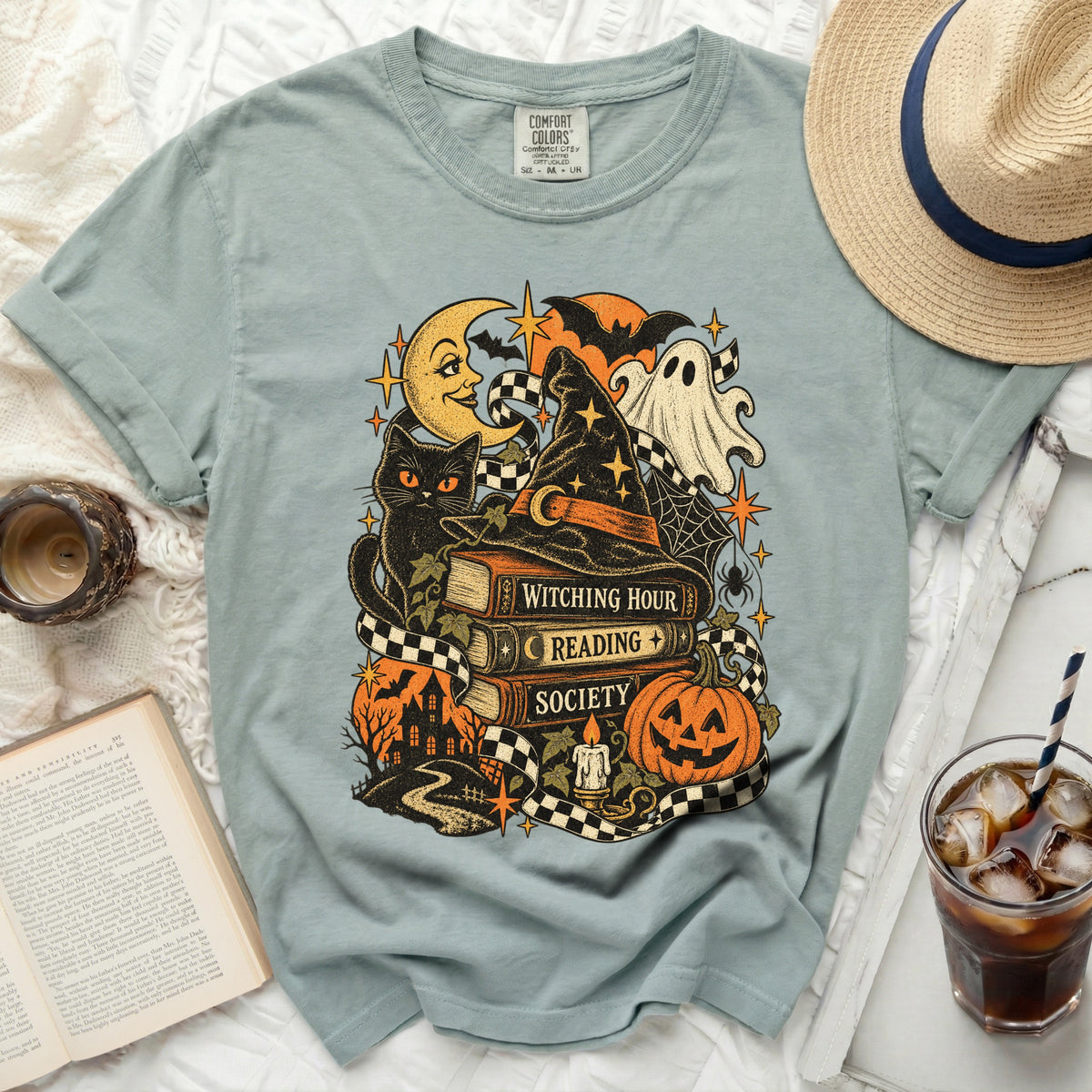 T-shirt with witchy Halloween graphic: black cat, books, ghost, pumpkin, and moon.