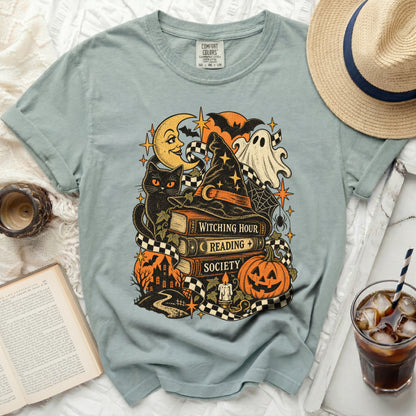 T-shirt with witchy Halloween graphic: black cat, books, ghost, pumpkin, and moon.