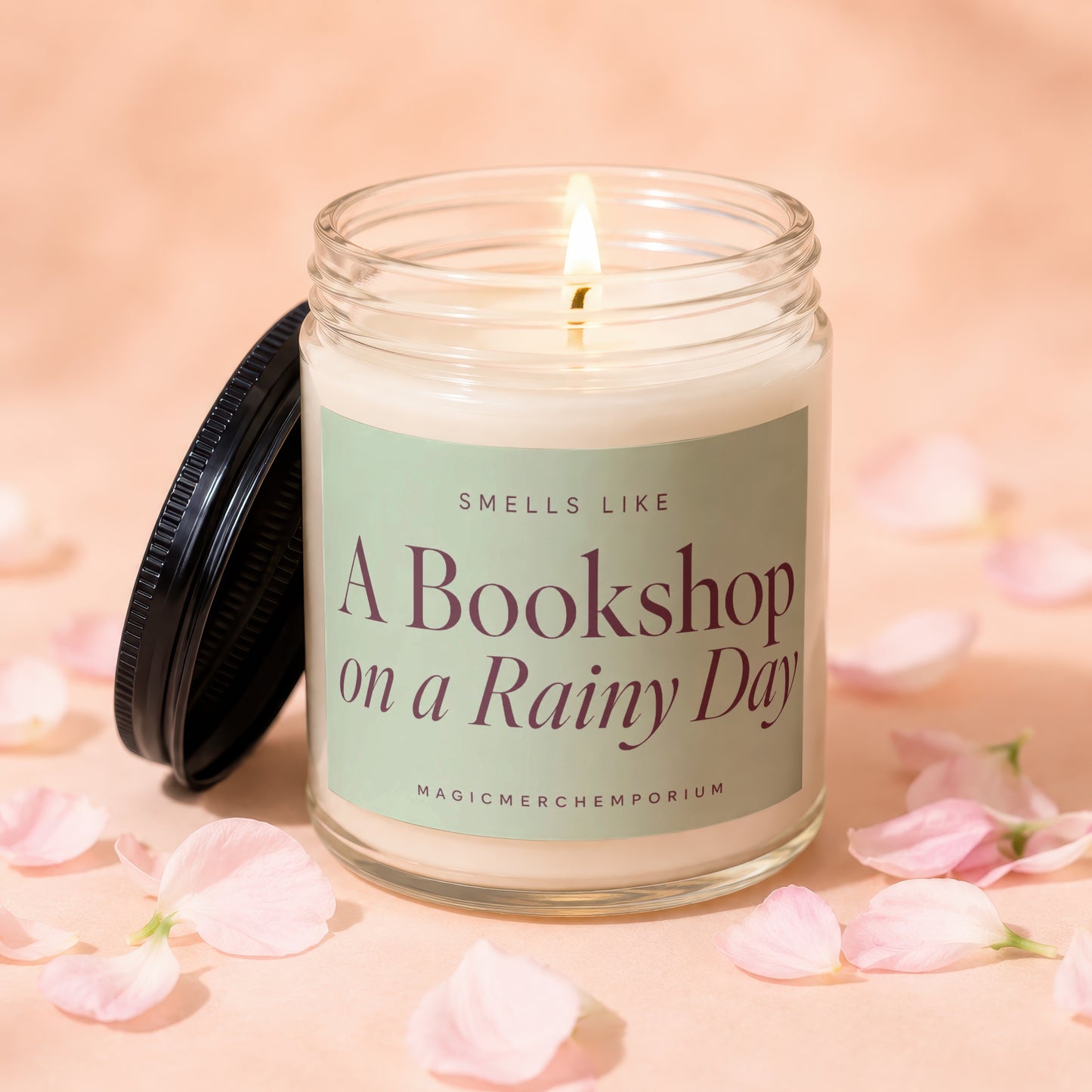 Candle with lit wick, label reads "Smells Like A Bookshop on a Rainy Day".