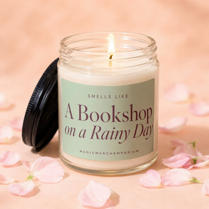 Candle with lit wick, label reads "Smells Like A Bookshop on a Rainy Day".