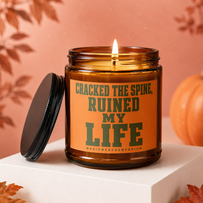 Amber candle lit with text "CRACKED THE SPINE, RUINED MY LIFE".