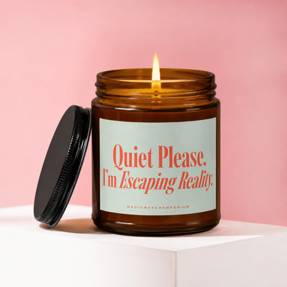 Amber glass candle with lit wick, lid beside it, reads "Quiet Please. I'm Escaping Reality."