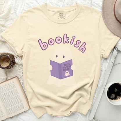 Cream t-shirt with a ghost reading a book titled "Tales to Keep Me Spooked."