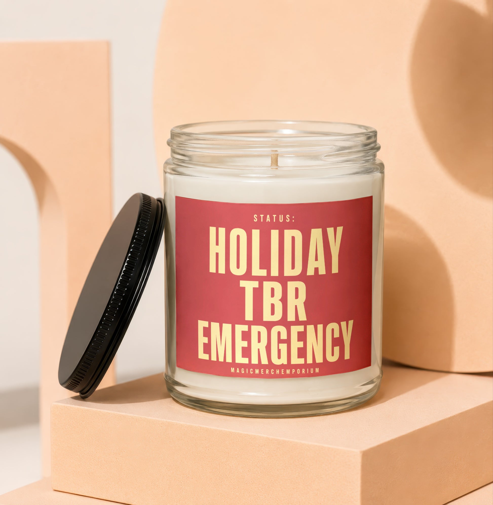 Glass candle with red label reading "STATUS: HOLIDAY TBR EMERGENCY"