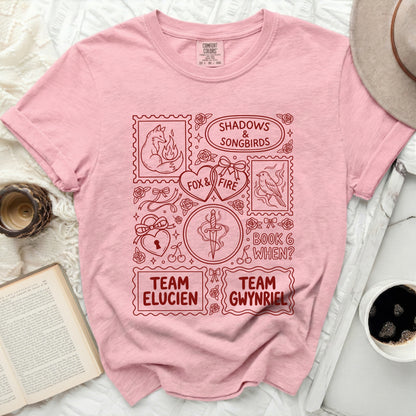 Pink t-shirt with red stamp-like graphics: fox, bird, dagger, hearts, text.