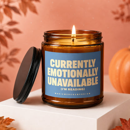 Amber jar candle with blue label reading "CURRENTLY EMOTIONALLY UNAVAILABLE (I'M READING)".