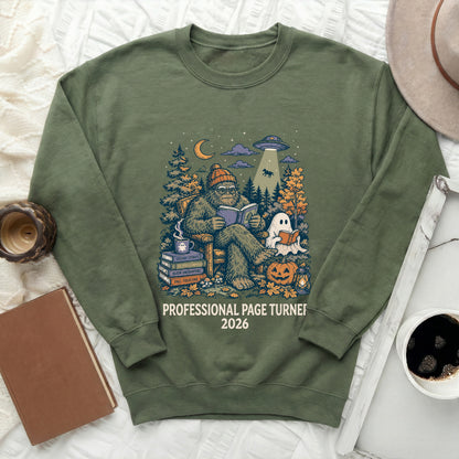 Green sweatshirt with Bigfoot, ghost, and UFO illustration. "Professional Page Turner 2026" text.