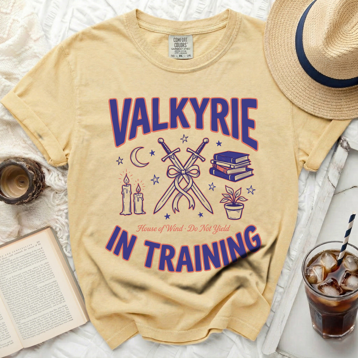 A yellow t-shirt features purple and blue graphic text that reads Valkyrie in Training, accompanied by crossed swords, books, and candles.
