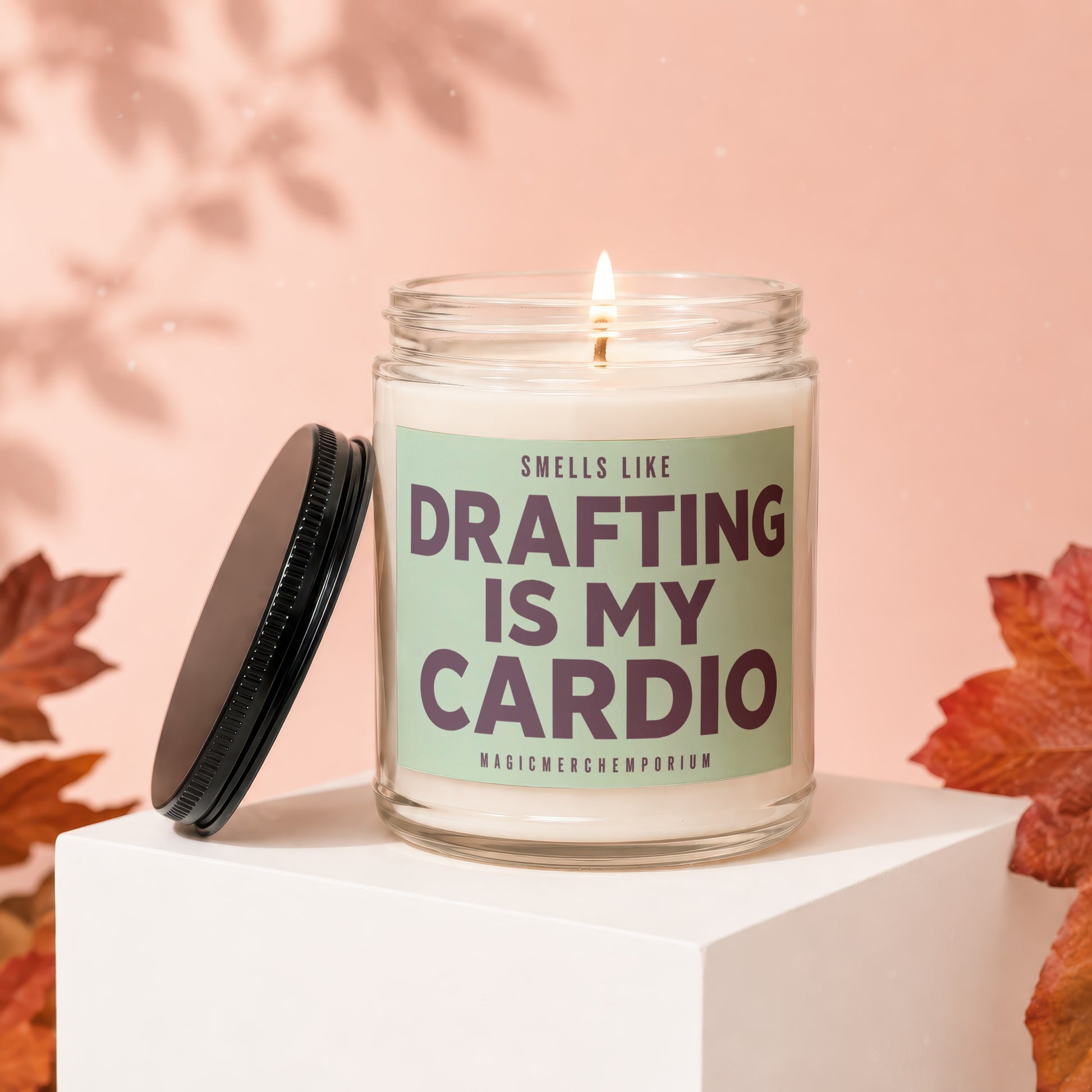 Lit candle in glass jar with label "Smells Like Drafting Is My Cardio".