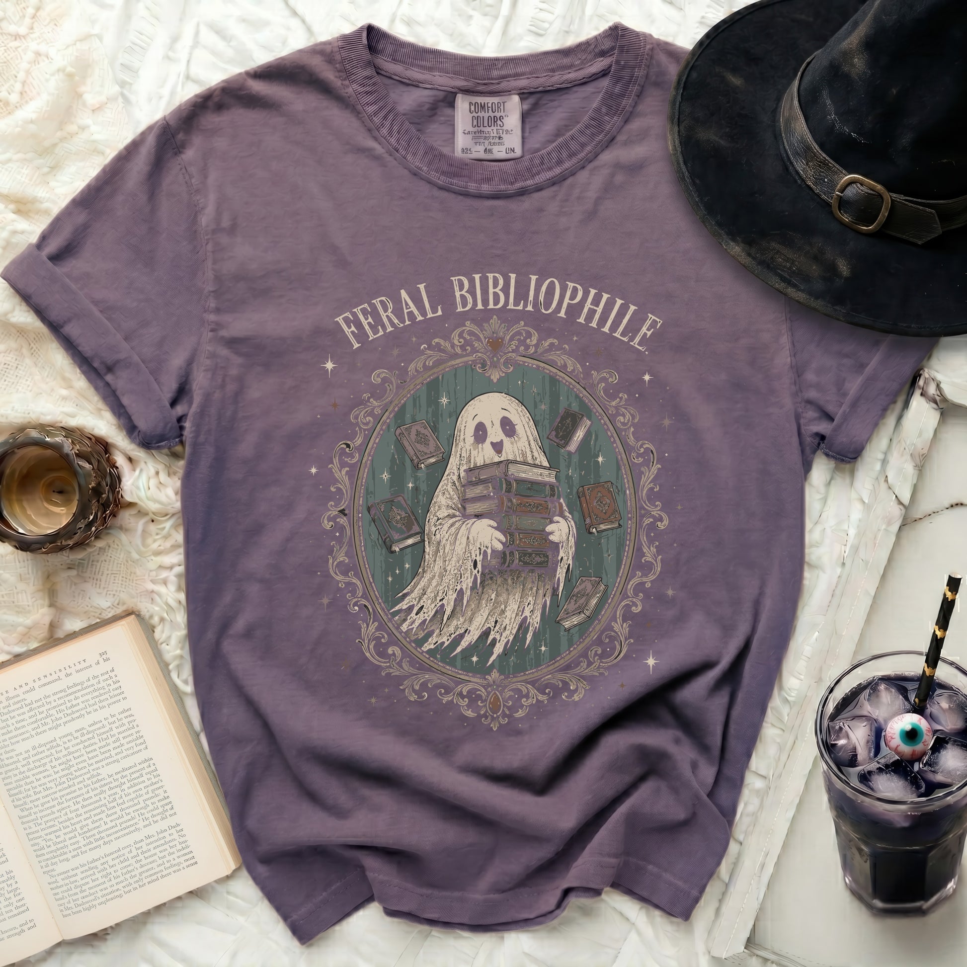 Purple t-shirt with a ghost character holding books and text "FERAL BIBLIOPHILE".