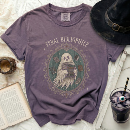 Purple t-shirt with a ghost character holding books and text "FERAL BIBLIOPHILE".