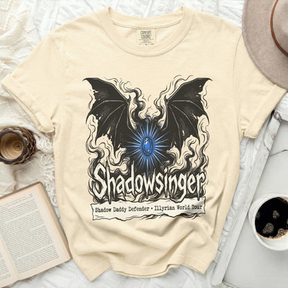Cream t-shirt with black graphic of wings, a blue gem, and text "Shadowsinger".