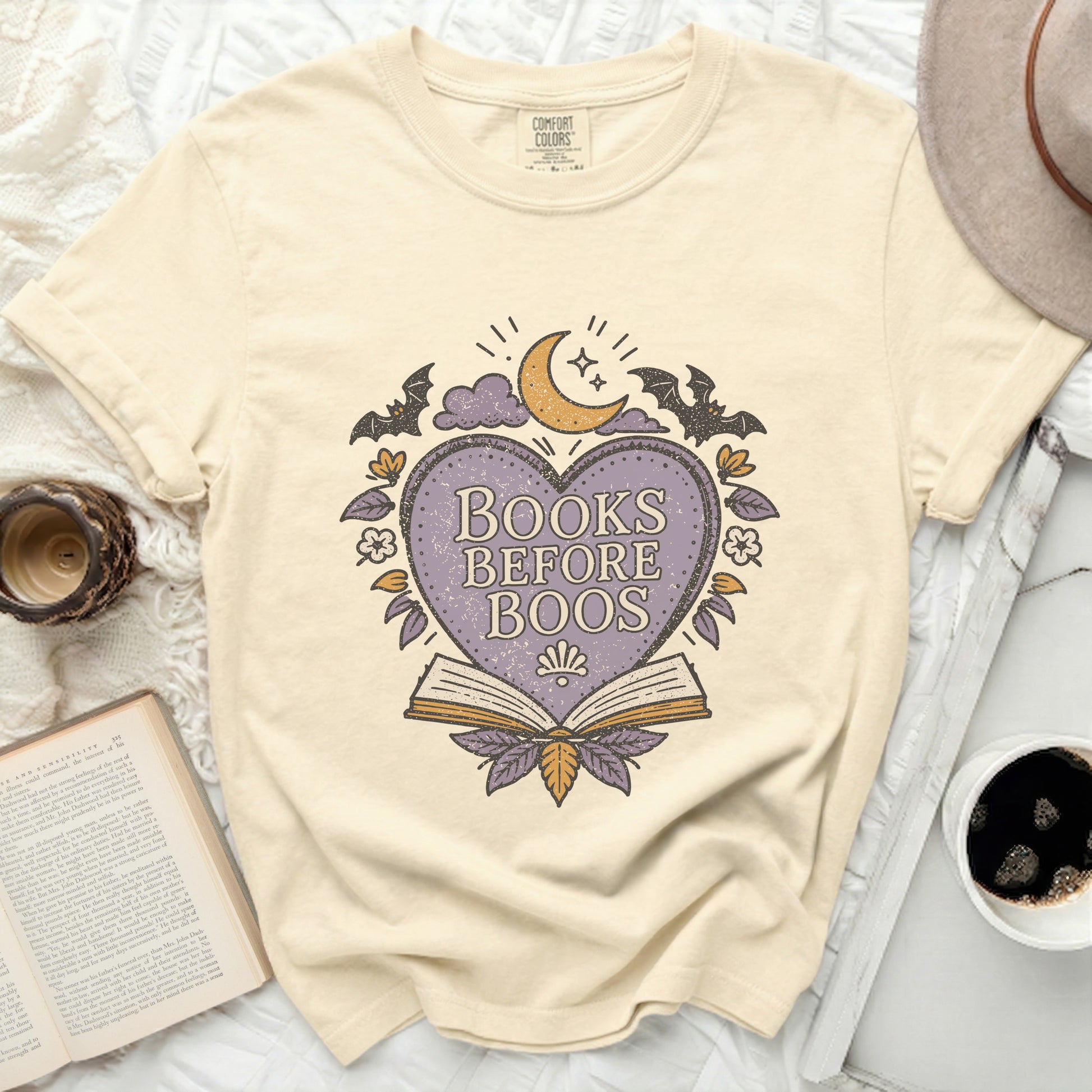 Cream t-shirt with "Books Before Boos" graphic featuring a heart, moon, and bats.