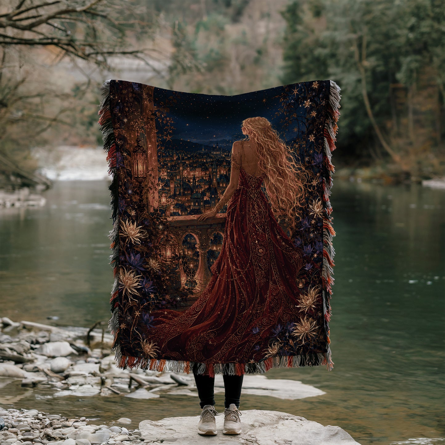 A person stands on a rock, holding a large tapestry that depicts a woman with long, flowing hair and a red dress, gazing out at a river or lake.