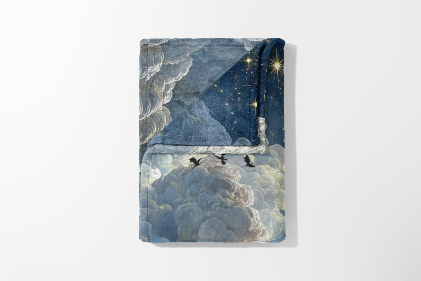 Folded blanket with a starry night sky and clouds, silhouetted birds flying.