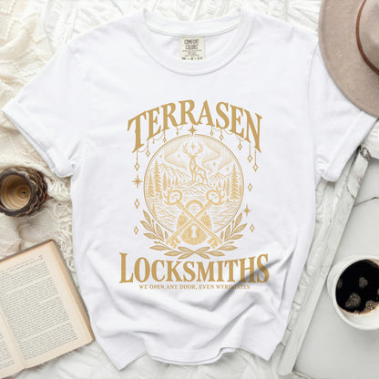 White t-shirt with gold text and graphic: TERRASEN LOCKSMITHS, WE OPEN ANY DOOR, EVEN WYRDGATES.