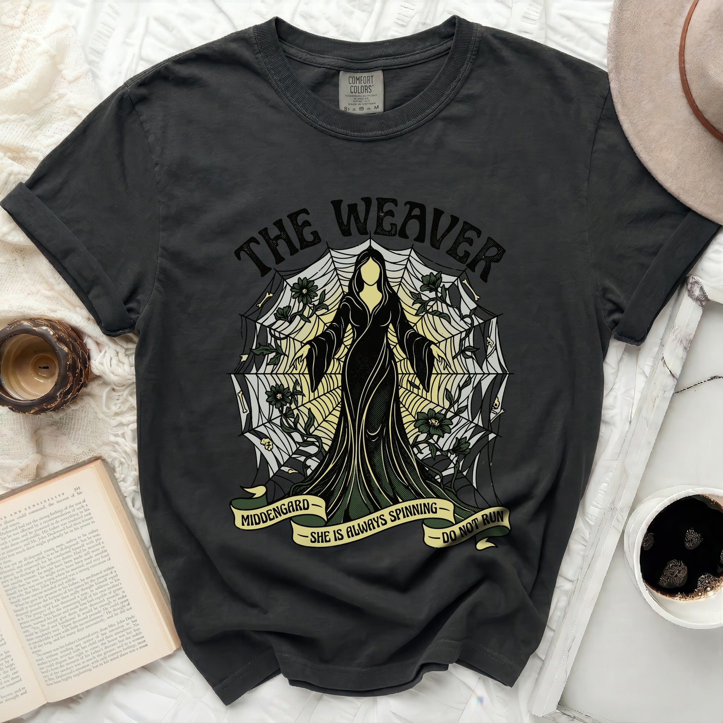T-shirt with "The Weaver" and spiderweb design, "MIDDENGARD" and "SHE IS ALWAYS SPINNING DO NOT RUN" text.
