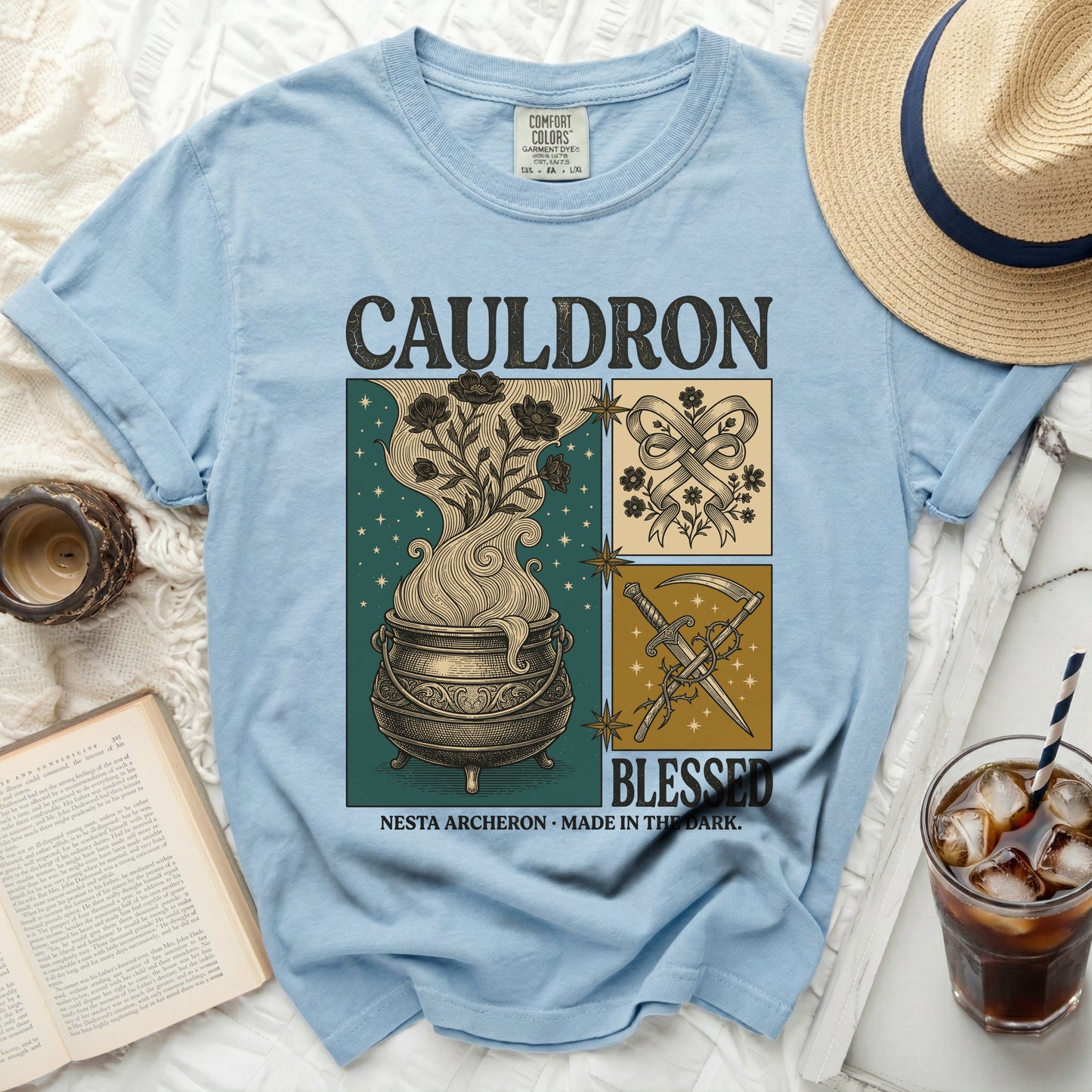 Light blue t-shirt with "CAULDRON BLESSED" and fantasy artwork.