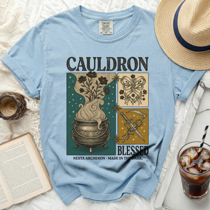 Light blue t-shirt with "CAULDRON BLESSED" and fantasy artwork.