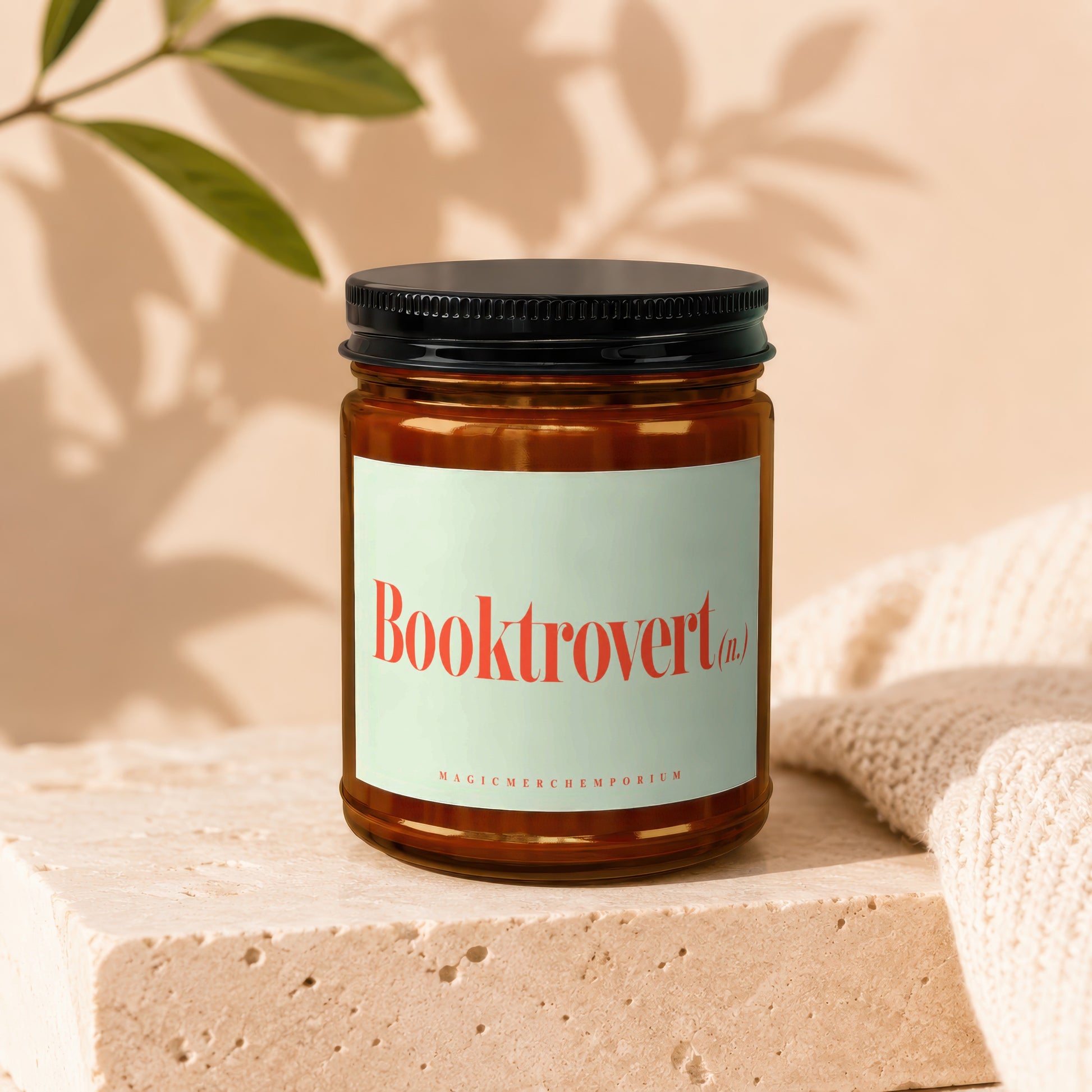 Amber candle with "Booktrovert (n.)" text on a light green label.