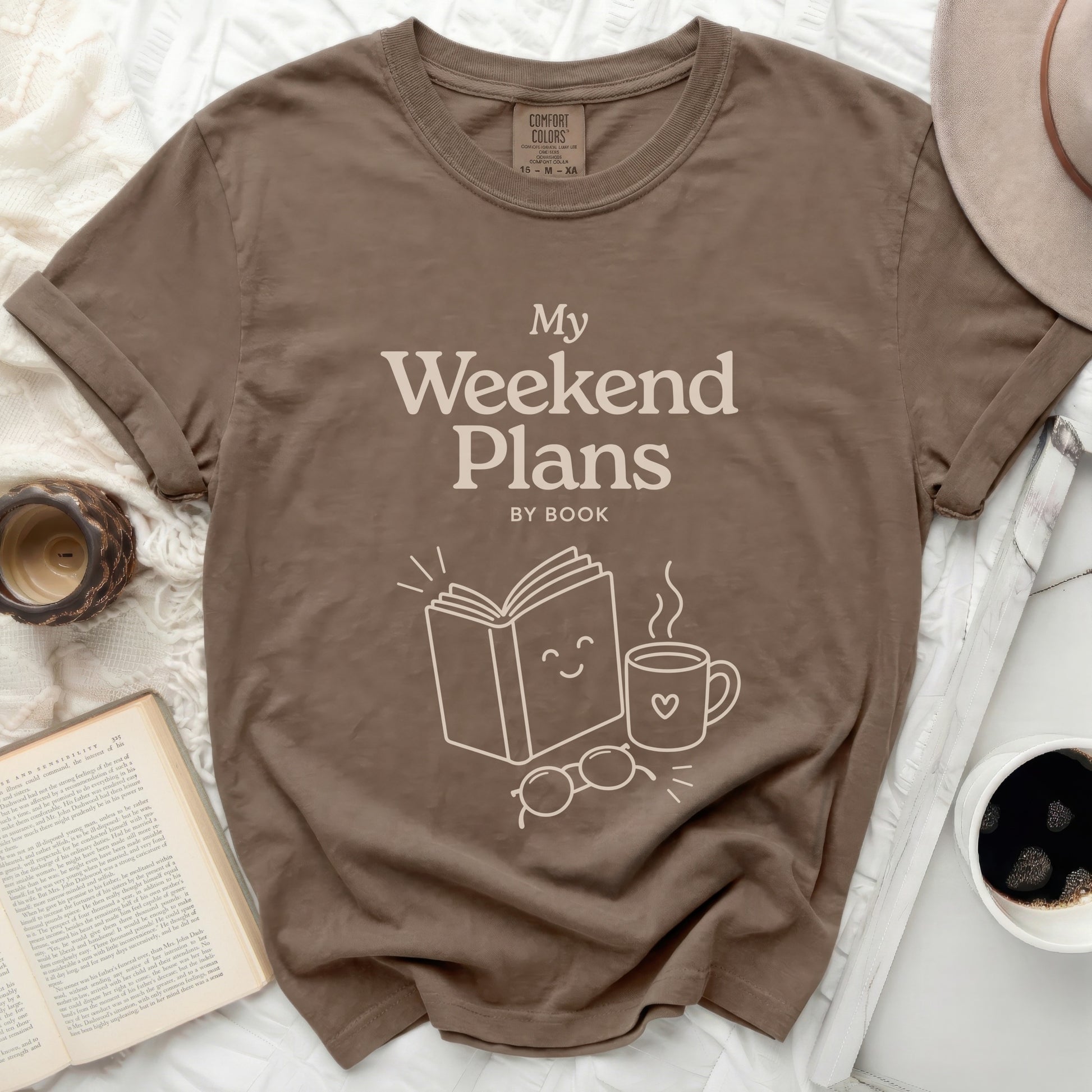 Brown t-shirt with "My Weekend Plans BY BOOK" graphic and book, mug, glasses.
