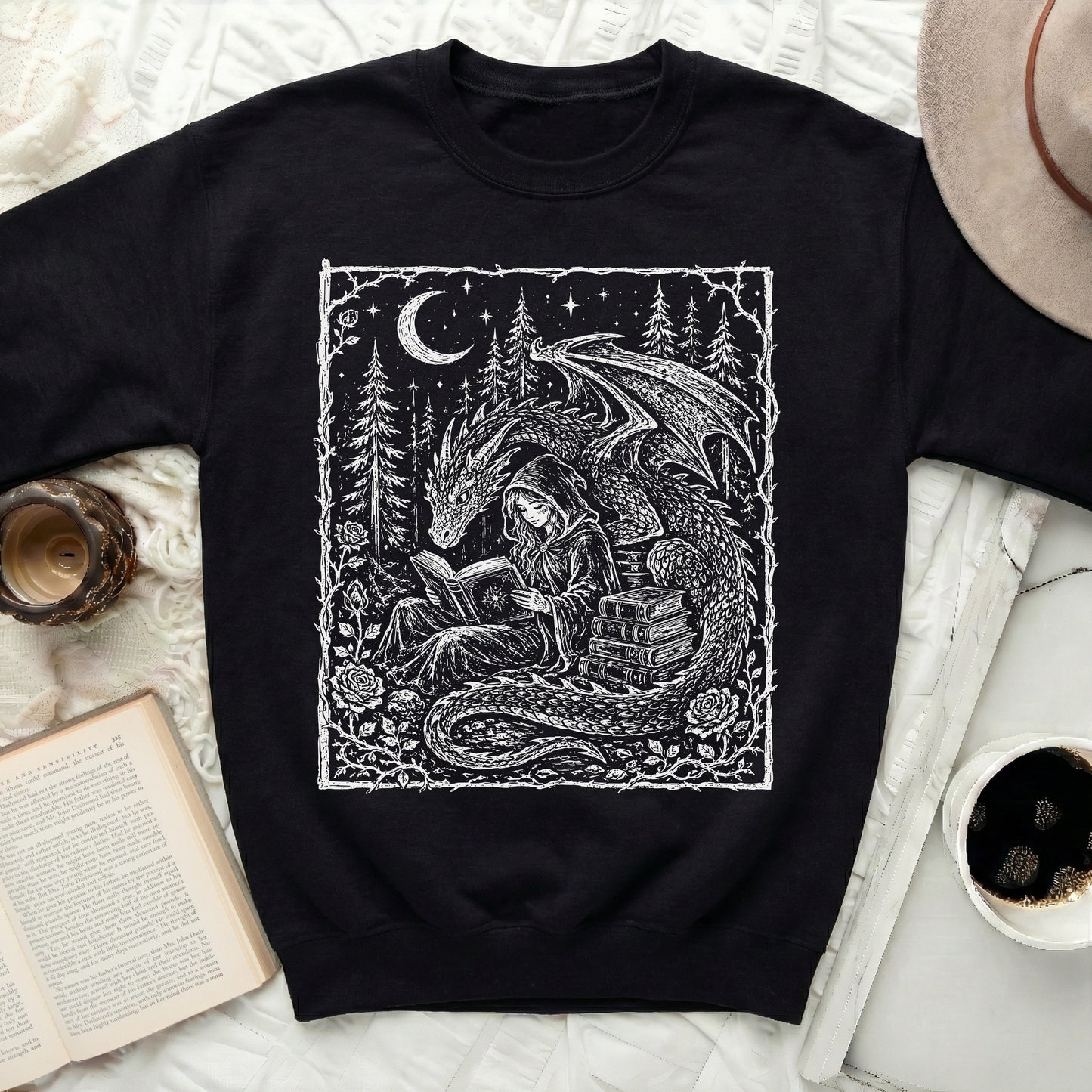 Black sweatshirt with white graphic of a dragon and a hooded figure reading a book.