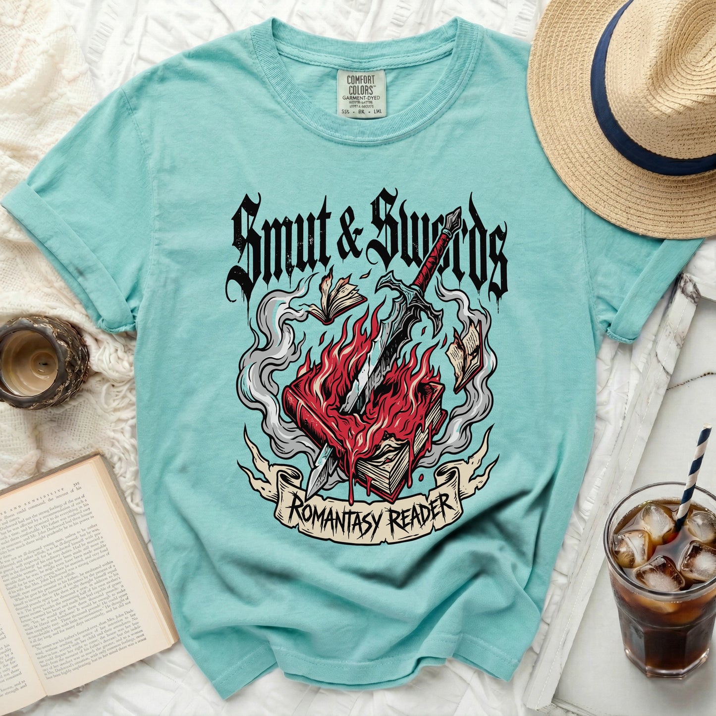 Aqua t-shirt with "Smut & Swords Romantasy Reader" graphic of flaming books and sword.