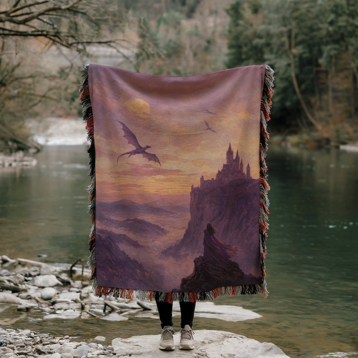 A person is standing on a rock, holding a large blanket that features a dragon and a castle in the background.