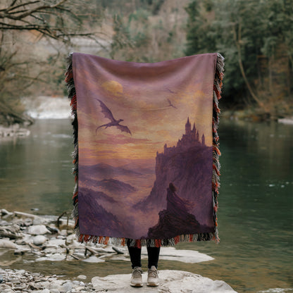 A person is standing on a rock, holding a large blanket that features a dragon and a castle in the background.