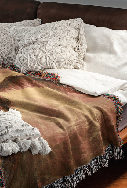 a cozy and inviting bedroom scene, featuring a bed with a brown blanket and white pillows, a brown leather couch, and a colorful throw blanket.