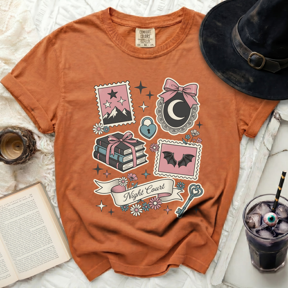 Orange Comfort Colors t-shirt with Night Court graphic featuring moon, bats, books, and stars.