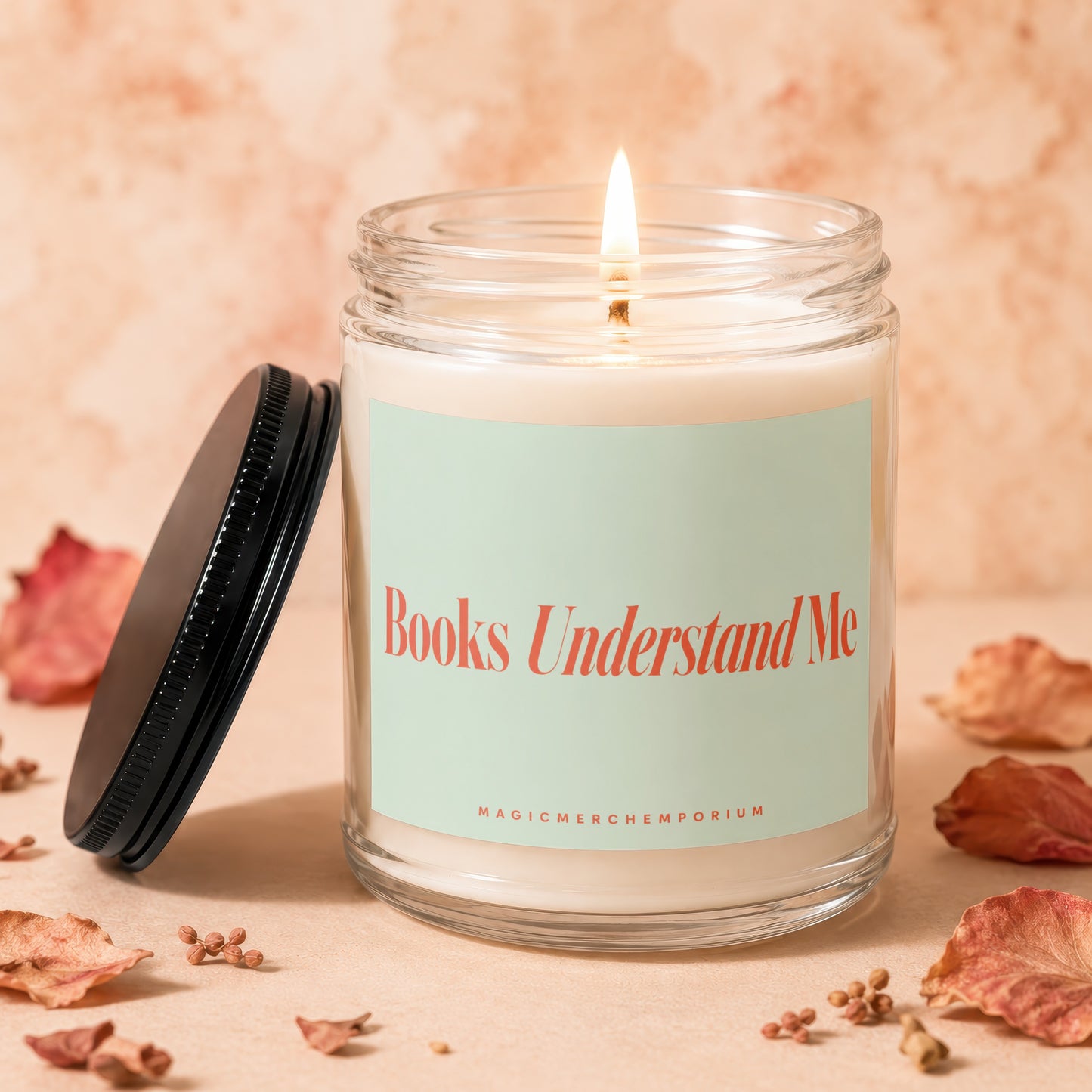 Glass candle with lit wick and "Books Understand Me" text
