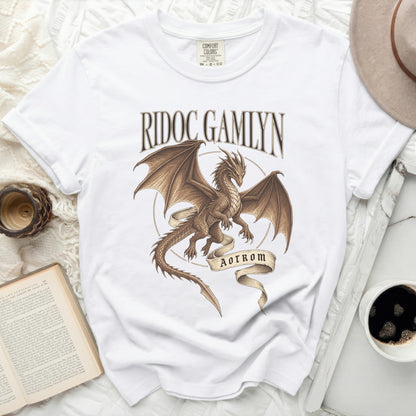 White t-shirt with a brown dragon graphic and text "RIDOC GAMLYN AOTROM".