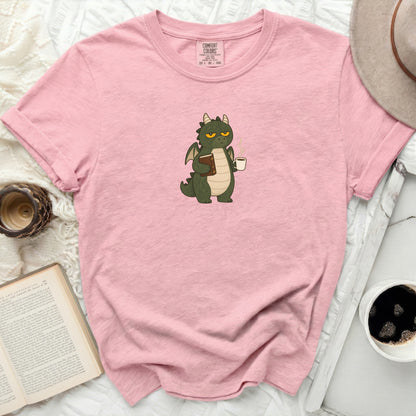 Pink t-shirt with a green dragon holding a book and coffee.
