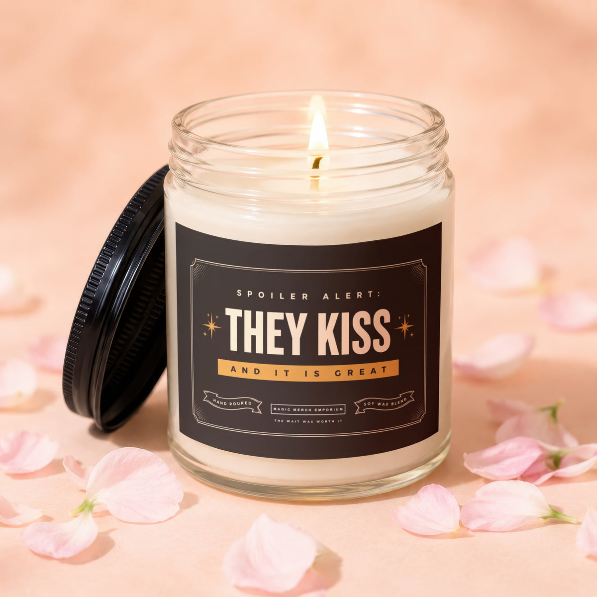 Candle with black lid, reading "Spoiler Alert: They Kiss and It Is Great".