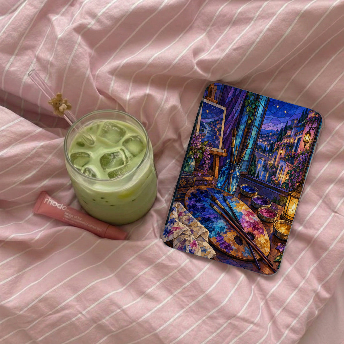Tablet with stained glass art of a European village scene and art supplies.