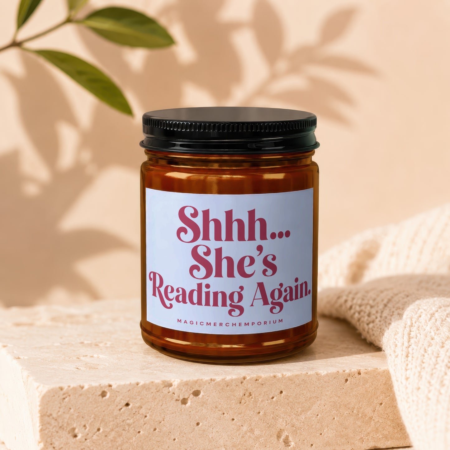 Amber jar candle with white label reading "Shhh... She's Reading Again."