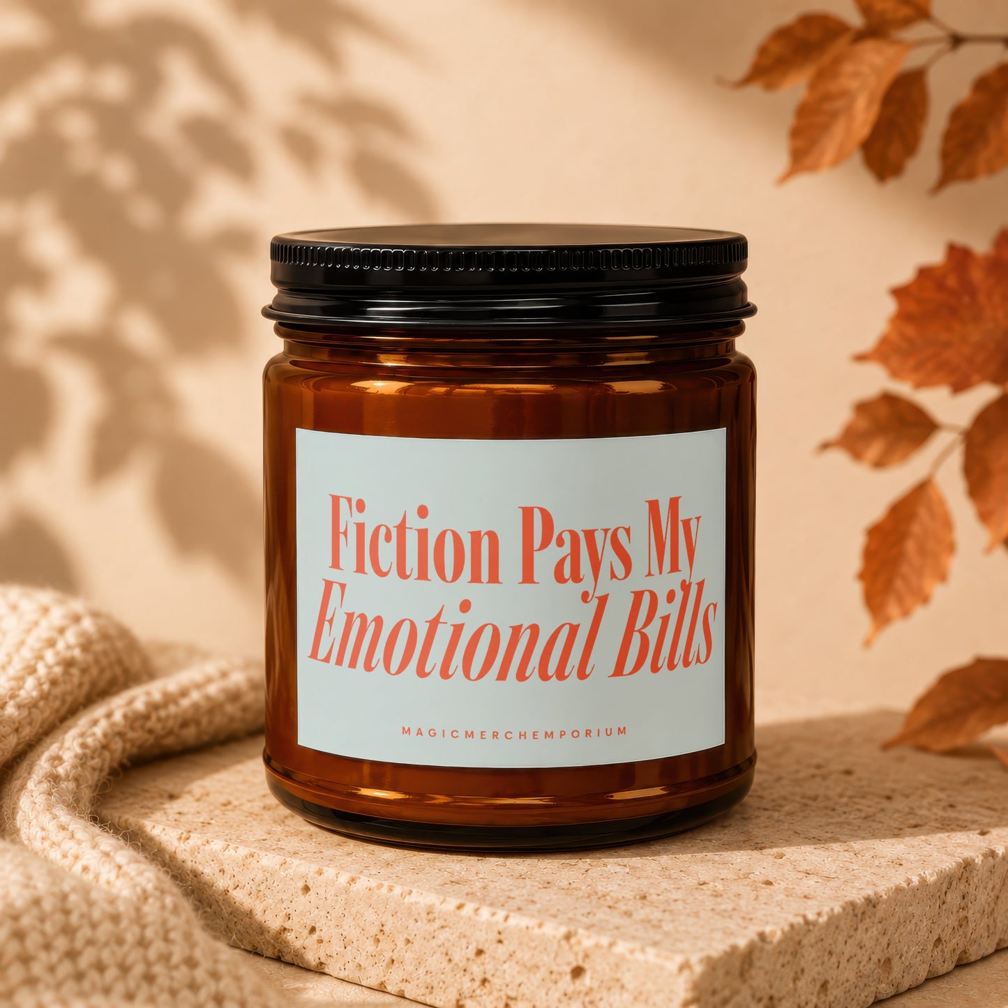 Amber glass candle with "Fiction Pays My Emotional Bills" text.