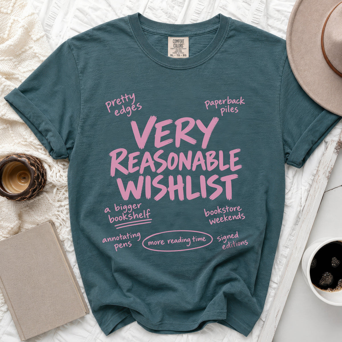 Dark teal t-shirt with pink text "VERY REASONABLE WISHLIST" and related phrases.