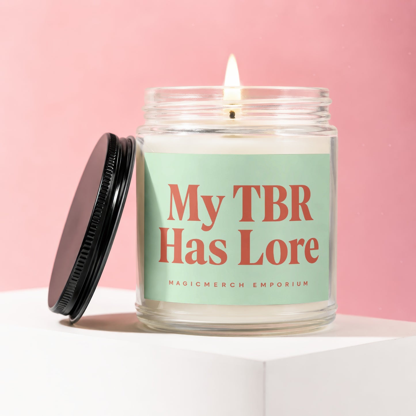 Candle with lit wick and black lid, reads "My TBR Has Lore"