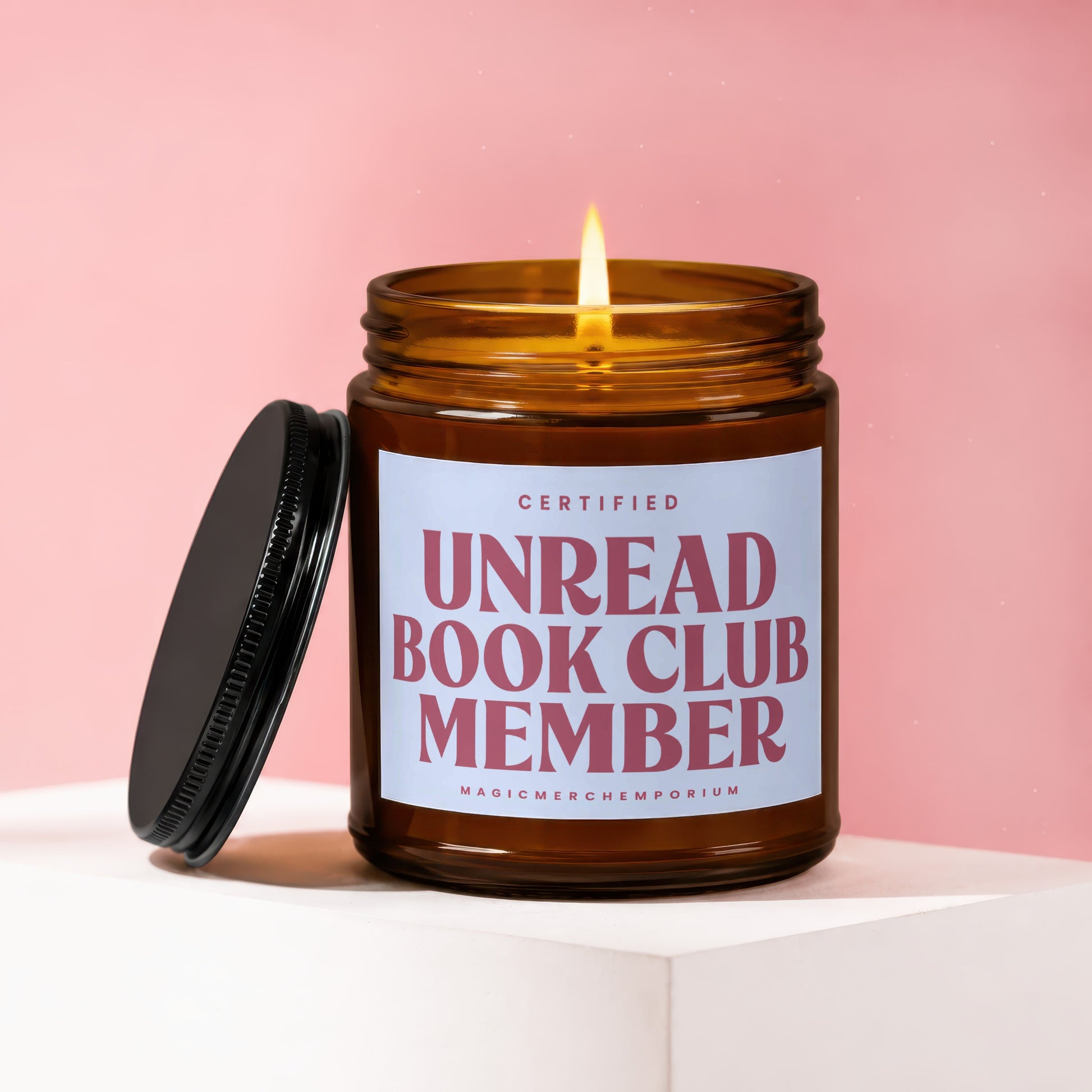 Amber jar candle with lit flame, labelled "Certified Unread Book Club Member".
