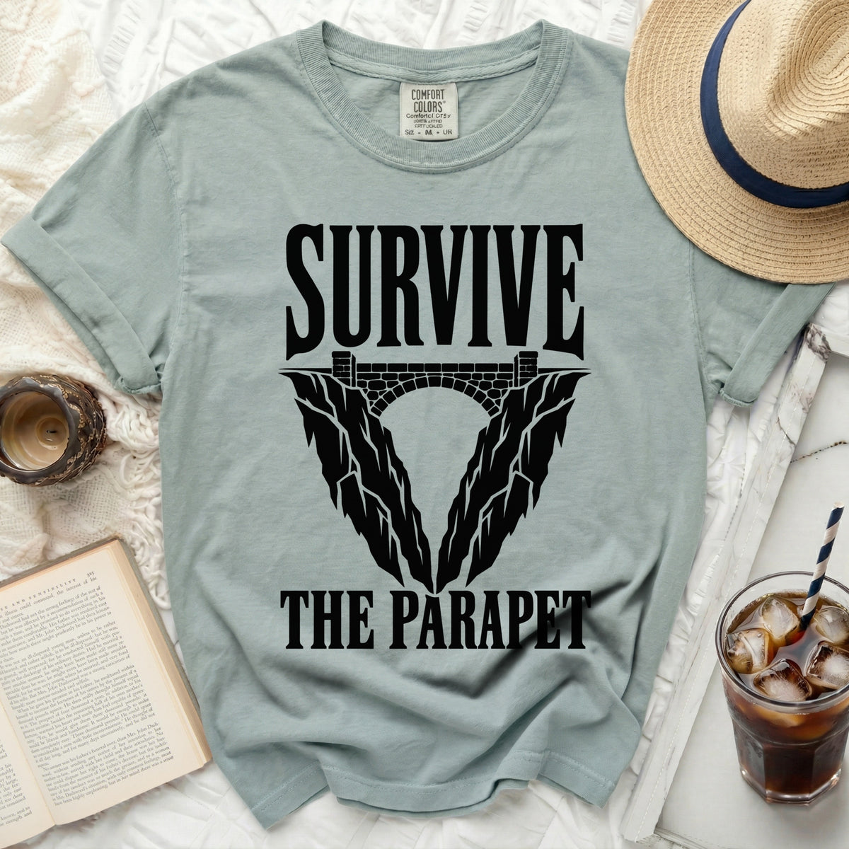 Light sage t-shirt with black text "SURVIVE THE PARAPET" and graphic.