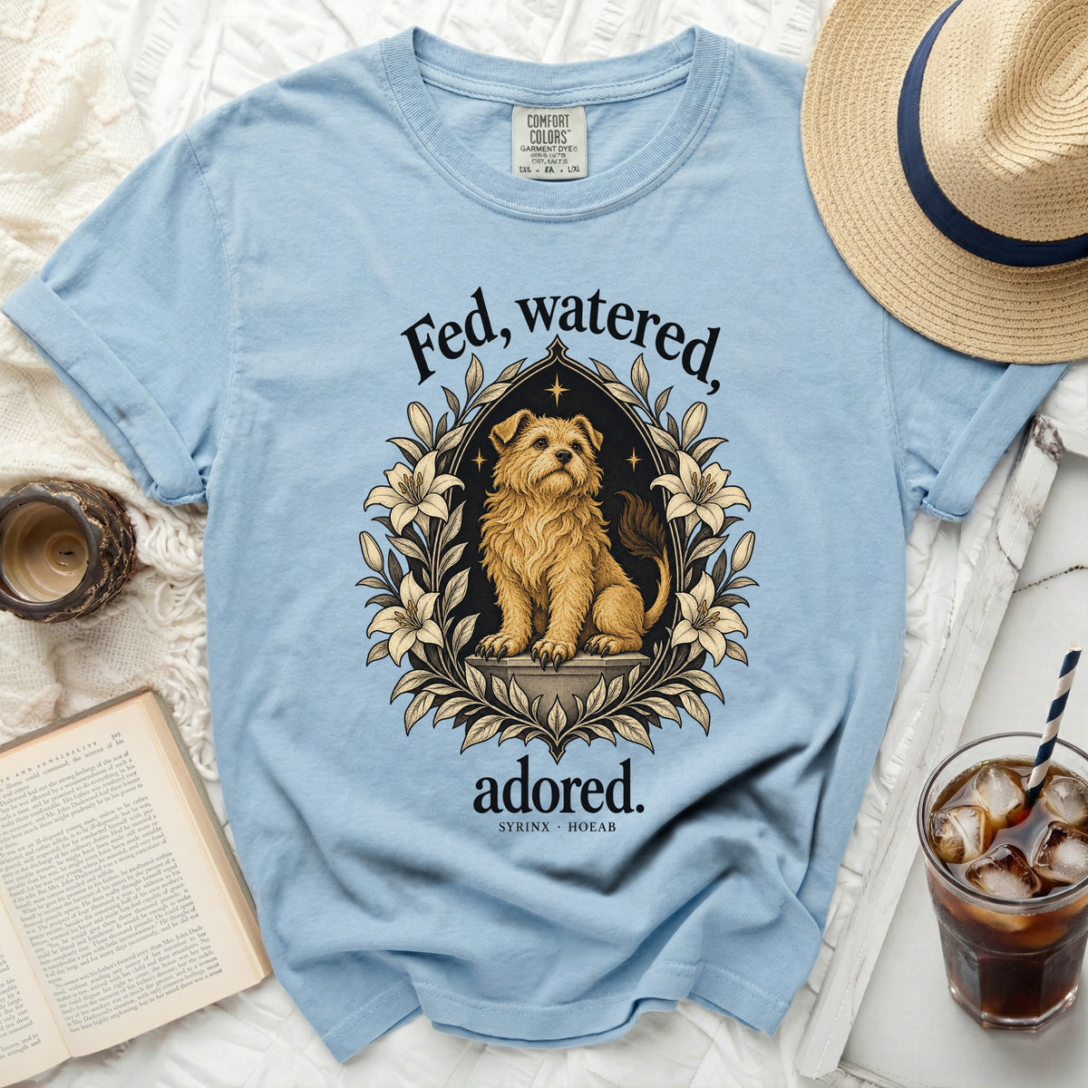 Light blue t-shirt with a framed illustration of a dog and the text "Fed, watered, adored."