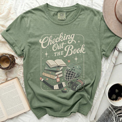 Green t-shirt with "Checking the Book" text and hockey gear illustration.
