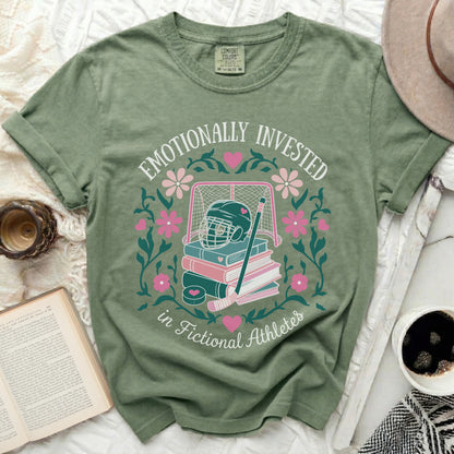 Green t-shirt with "Emotionally Invested in Fictional Athletes" text and sports graphics.