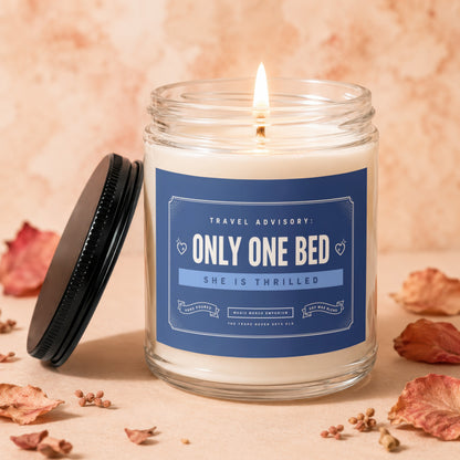 Candle with blue label reading "ONLY ONE BED" and "SHE IS THRILLED."