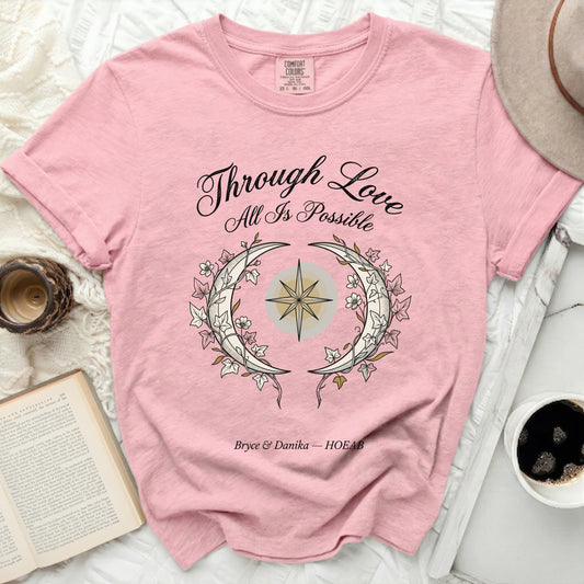 Pink t-shirt with "Through Love All Is Possible" design.