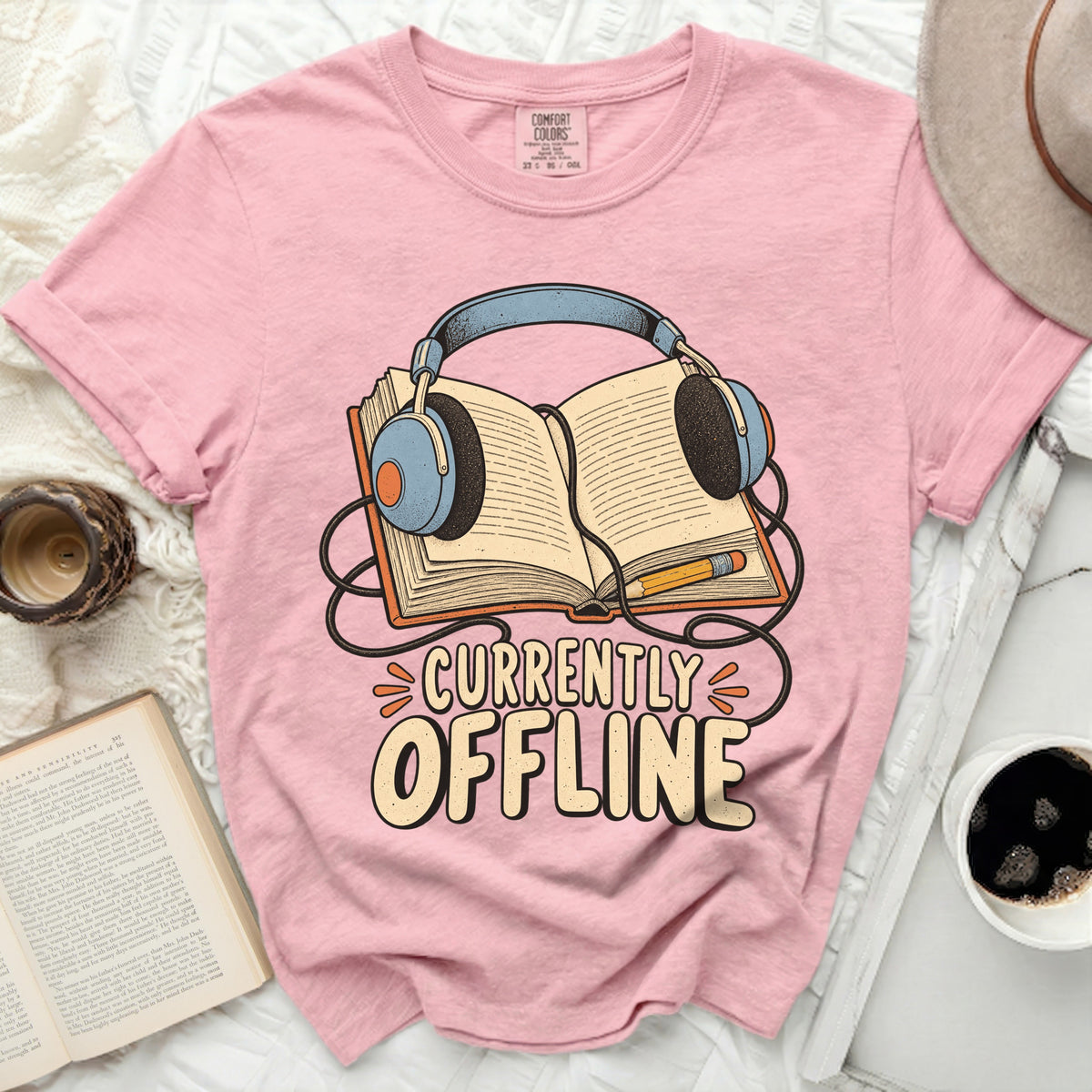 Pink t-shirt with "Currently Offline" text and headphones on an open book.