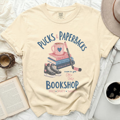 T-shirt with "Pucks & Paperbacks" bookshop design: books, skates, and hockey stick.