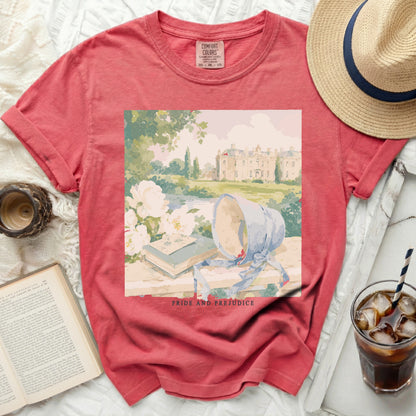Coral t-shirt with Pride and Prejudice graphic of a manor and books.